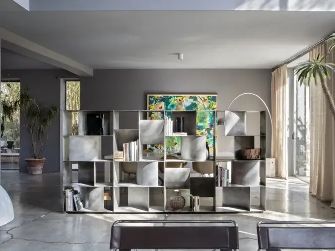 Judd Base contenitore da Terra in finitura Materico Lithos in una living room con piante, sedie, lampade e libri.