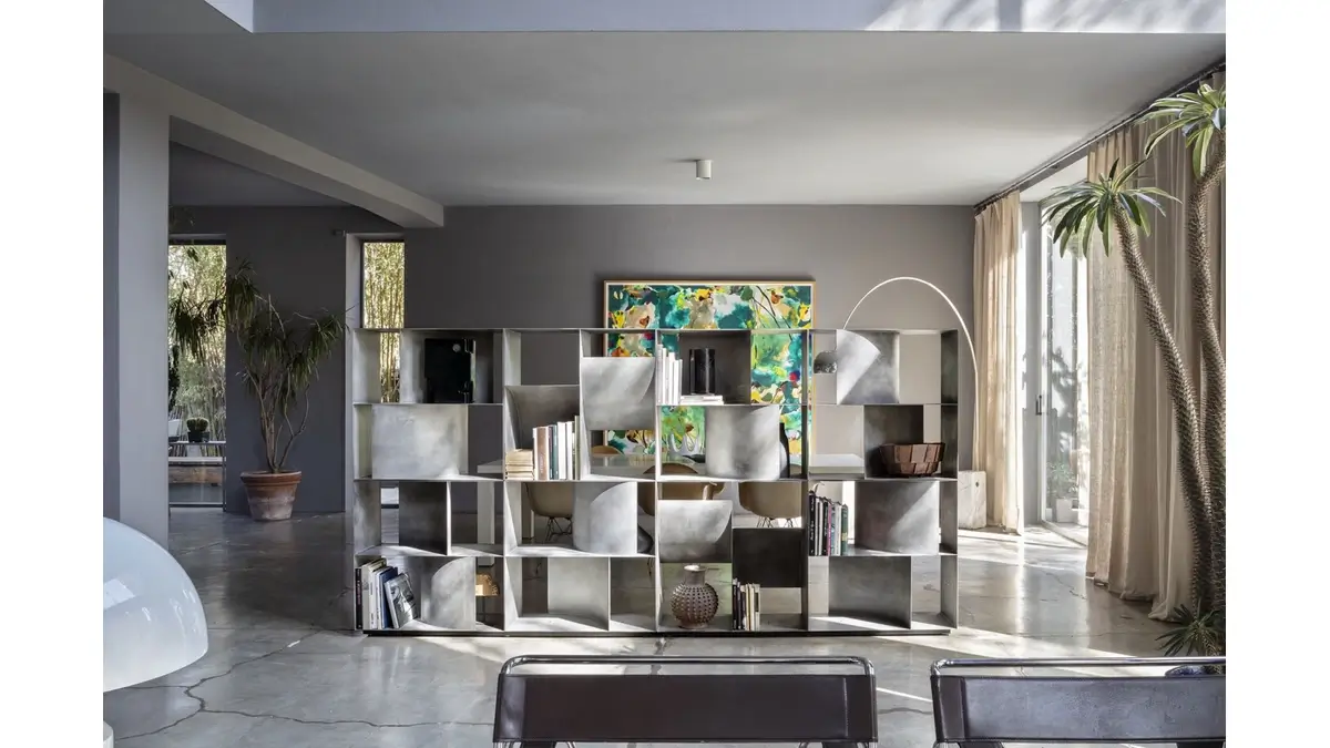 Judd Base contenitore da Terra in finitura Materico Lithos in una living room con piante, sedie, lampade e libri.