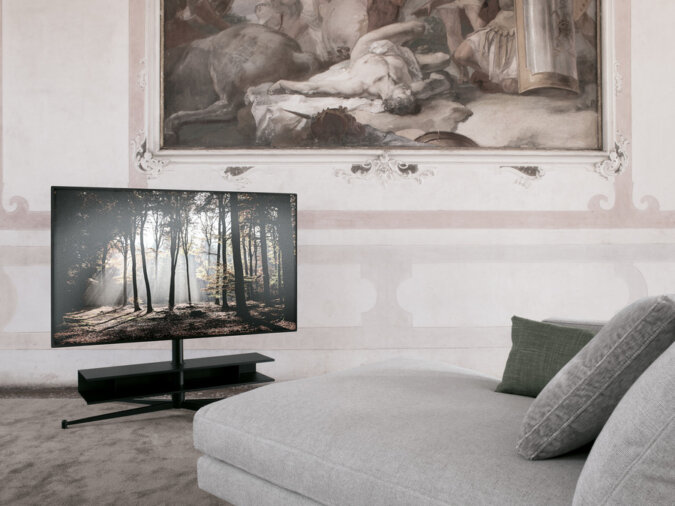 PortaTv Titano in finitura nera con TV accesa in una stanza con divano ed un quadro