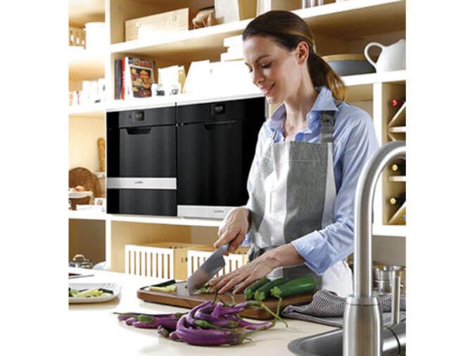 Donna in cucina che taglia zucchine su un piano con dietro due abbattitori Life W60