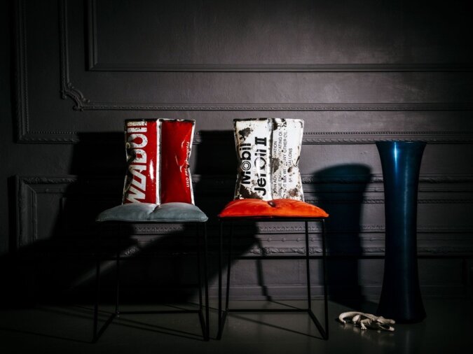 Due sedie Aria in lamiera di bidone rosso e bianco con cuscini sulla seduta in una living room con un vaso di vetro blu ed un coccodrillo di porcellana.