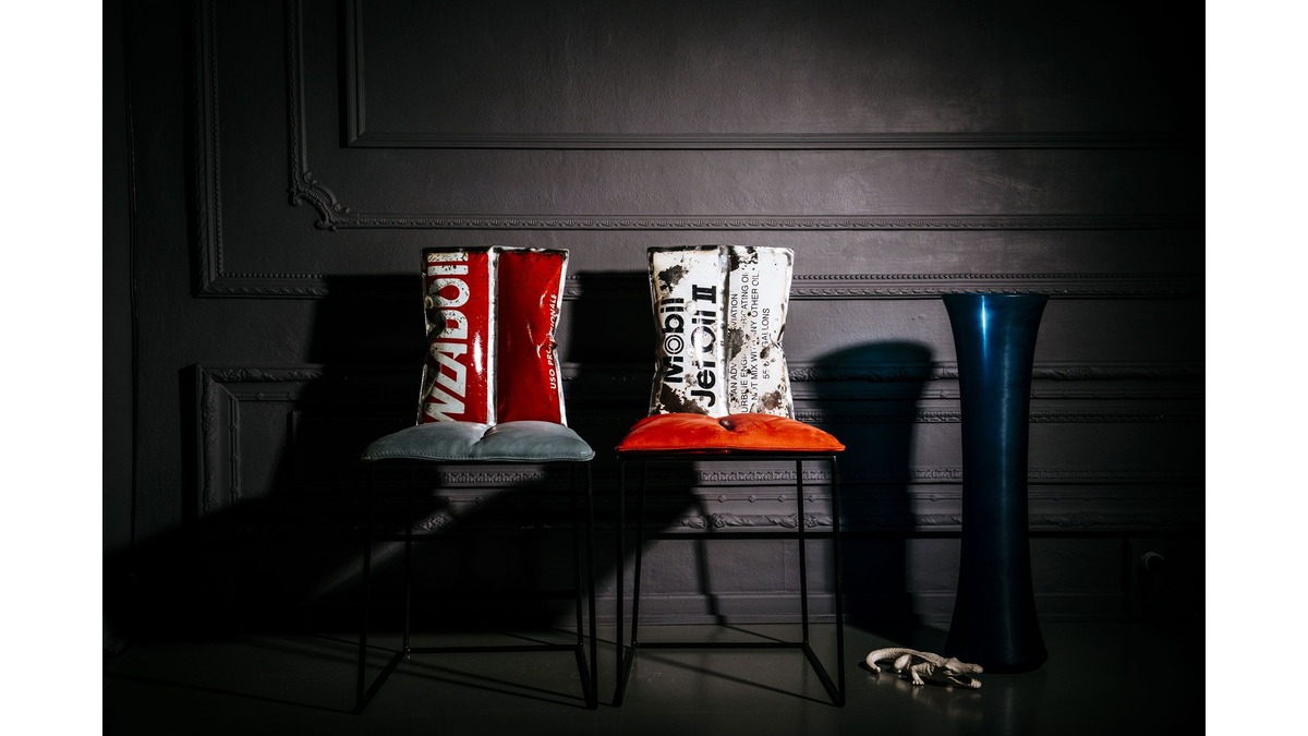 Due sedie Aria in lamiera di bidone rosso e bianco con cuscini sulla seduta in una living room con un vaso di vetro blu ed un coccodrillo di porcellana.
