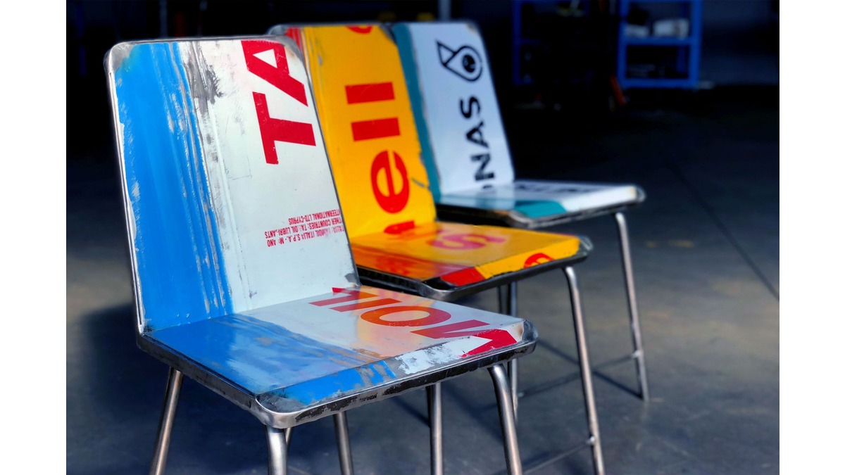 Primo piano di tre Avio Sedie in lamiera di bidone blu-bianco, giallo-rosso e verde-bianco di varie aziende. Sono poste in un garage.
