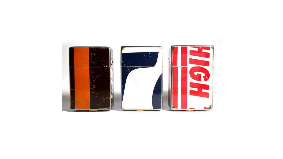 Tre Ciggy Box contenitore per pacchetto di sigarette in lamiera di bidone in vari colori su uno sfondo bianco.