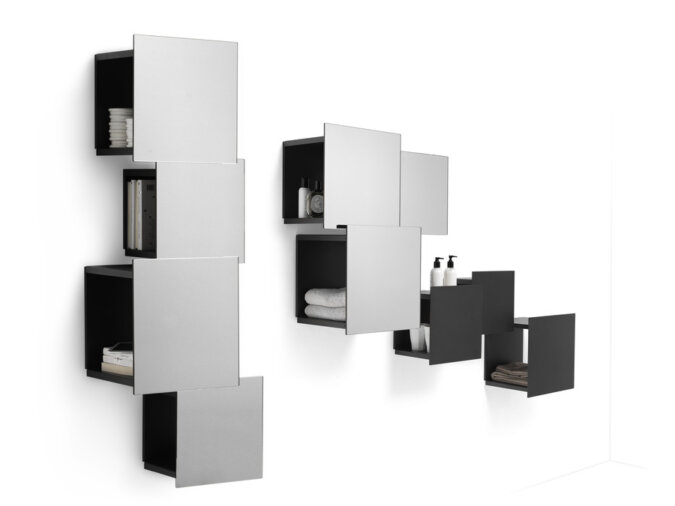 Dettagli della composizione di scaffali modulari DPI libreria a parete in finitura metallo antracite con libri ed oggetti poggiati all'interno dei vari moduli.