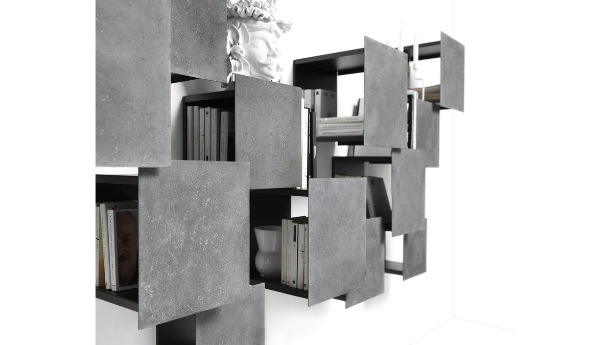 Dettagli della composizione di scaffali modulari DPI libreria a parete in finitura grigio lava con libri ed oggetti poggiati all'interno dei vari moduli.
