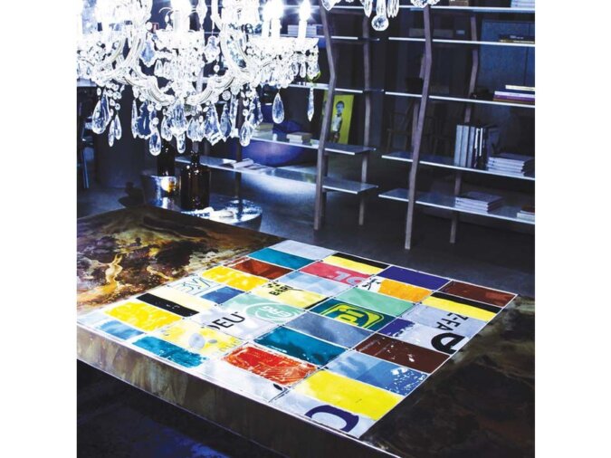 Dettagli colorati del Tavolo Easytable in lamiera di bidone. Sullo sfondo una libreria in ferro e sopra un Pendant Lamp in cristallo.