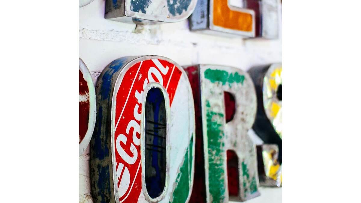 Dettagli di Font lettere in lamiera di bidone rosso e verde con scritta Castrol. Si vedono le lettere O, R e S