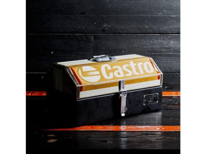 Cassetta degli attrezzi GT Toolbox in lamiera di bidone di Castrol appoggiata su un piano di legno nero con fasce arancioni.