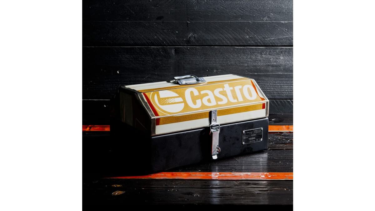 Cassetta degli attrezzi GT Toolbox in lamiera di bidone di Castrol appoggiata su un piano di legno nero con fasce arancioni.