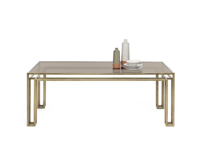 Hotline table con struttura in finitura Bronzo Patinato e un piano trasparente, apparecchiato con una bottiglia e dei piattini.