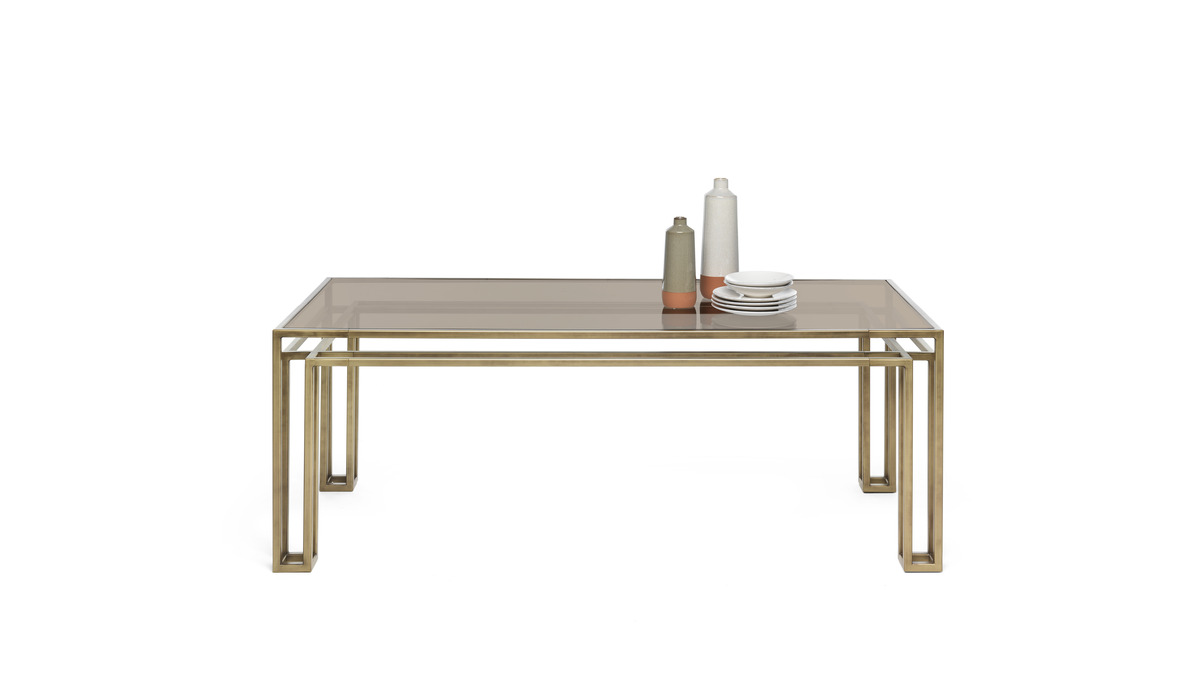 Hotline table con struttura in finitura Bronzo Patinato e un piano trasparente, apparecchiato con una bottiglia e dei piattini.