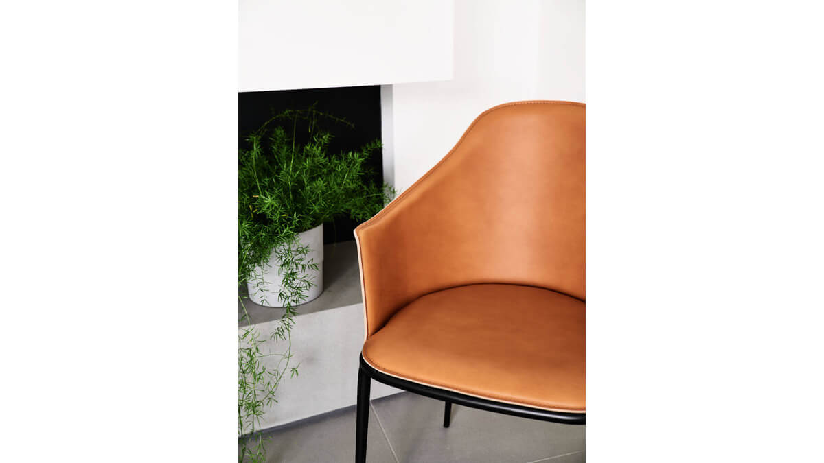 Sedia Lea in cuoio Arancione con una pianta sul lato.