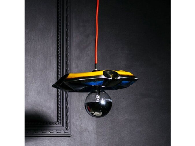 Primo piano di Nuvola Pendat lamp in lamiera di bidone gialla e blu con lampadina ed una corda rossa che la sostiene.