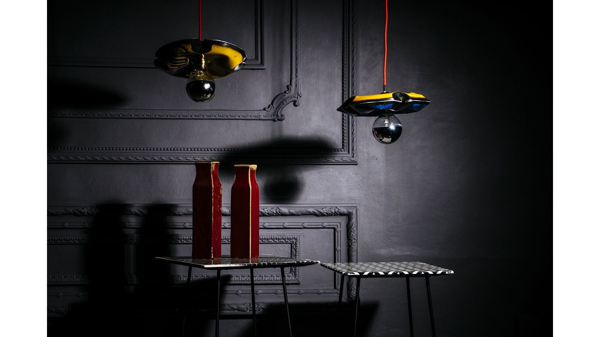 Due Pendant Lamps Nuvola in lamiera di bidone gialla contro un muro grigio scuro. Sotto due tavolini in ferro ornati con vasi.