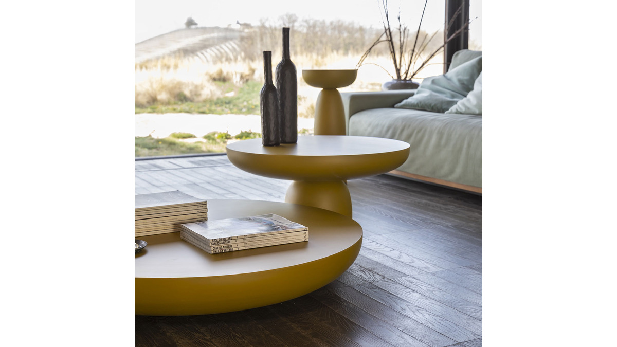 Living Room moderno caratterizzato da vari Olo Coffee Tables con bottiglie e libri, sullo sfondo un comodo divano e una serena vista all'aperto.