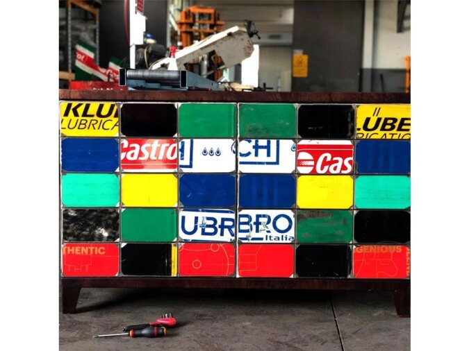 Dettagli della Madia Ono in lamiere di bidone di vari colori con varie scritte, posta in un garage con attrezzi.