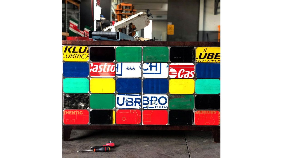 Dettagli della Madia Ono in lamiere di bidone di vari colori con varie scritte, posta in un garage con attrezzi.