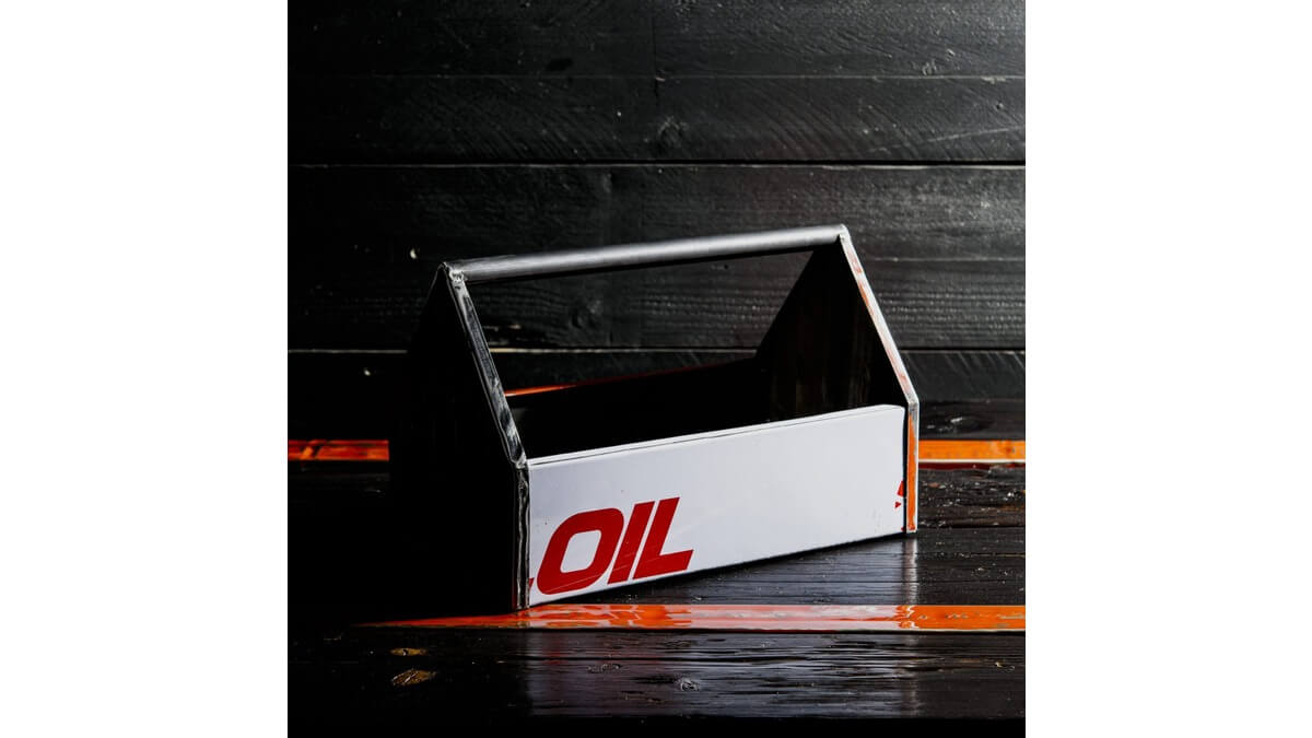 Cassetta degli attrezzi Petrolhead Toolbox in lamiera di bidone OIL, appoggiata su un piano di legno nero e arancione.