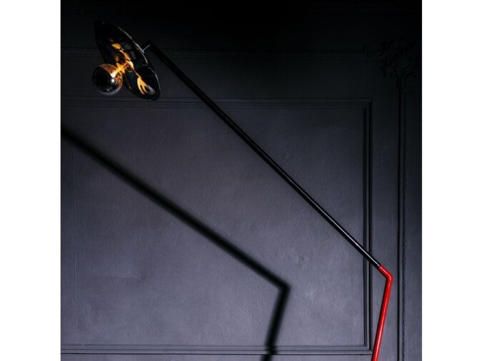 Lampada da terra Settanta in lamiera di bidone rossa e nera con lampadina spenta. Posta in una stanza poco illuminata.